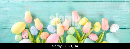 Primavera e Pasqua sfondo vacanze con fiori di tulipano, colorate uova pastello su tavolo blu vista dall'alto. Buon biglietto d'auguri pasquale. Foto Stock