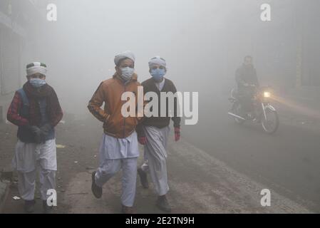 Lahore, Pakistan. 15 gennaio 2021. I pendolari pakistani e la gente fanno il loro senso fra la nebbia densa in una mattina fredda di inverno a Lahore. L'intensità della nebbia, la visibilità è stata ridotta a zero, rendendo difficile la manovra dei veicoli sulle strade. La polizia stradale ha emanato linee guida per la sicurezza delle persone dopo che la nebbia è entrata in città: La visibilità deve ridursi a meno di 1 chilometro, i livelli di umidità devono essere superiori al 90 per cento, l'aria deve essere ferma e il cielo deve essere limpido. Solo allora ci sono possibilità di nebbia. (Foto di Rana Sajid Hussain/Pacific Press/Sipa USA) Credit: Sipa USA/Alamy Foto Stock