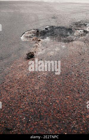 Buco profondo nell'asfalto sulla strada - danneggiato fondo stradale - stagione fredda Foto Stock