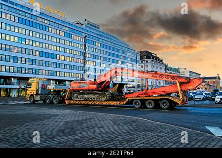 Mercedes-Benz Actros autocarro con caricatore basso rimorchio Ruoppaustio trasporta l'escavatore Doosan DX 300 LC in città al crepuscolo. Helsinki, Finlandia. 19 dicembre 2019. Foto Stock