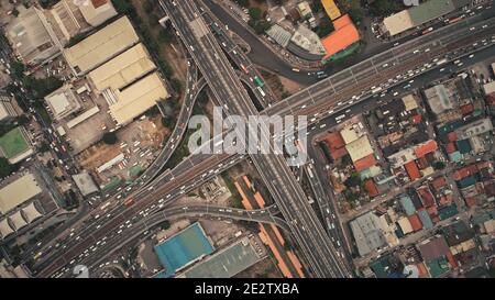 In alto verso il basso del traffico stradale con auto, camion, veicoli in vista aerea. Centro di Manila città con edifici colorati tetti sulla strada. Filippine stile di vita urbano con viaggio locale Foto Stock
