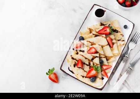 Frittelle crespate sottili con salsa al cioccolato e fragola fresca, vista dall'alto. Foto Stock