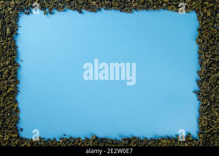 Cornice di foglie di tè secco su sfondo blu con posto per il testo Foto Stock