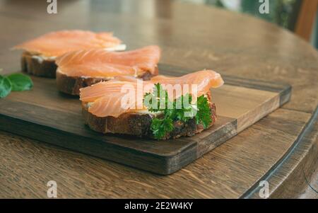 Panini al salmone affumicato con il pane di fico su un tavolo di legno, concetto di nutrizione sana, fuoco selettivo Foto Stock