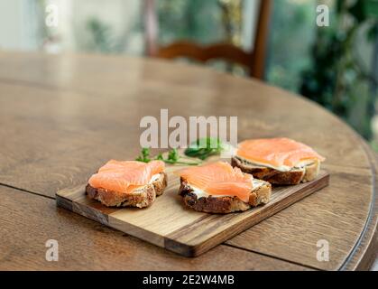 Colazione salutare con panini al salmone aperti su pane di fichi un tavolo di legno Foto Stock