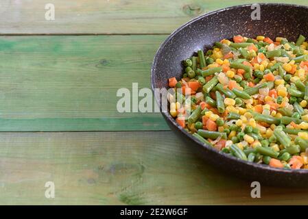 Mescolare le verdure fritte nella padella su sfondo di legno. Spazio di copia. Concetto di cibo sano. Foto Stock