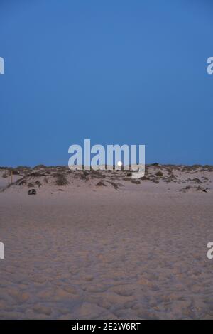 Spiaggia vuota di notte con luna dietro la duna di sabbia a porta, Portogallo Foto Stock