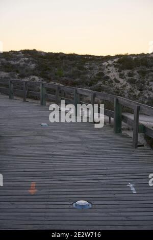 Lungomare con frecce direzionali distanza sociale al tramonto a Comporta, Portogallo Foto Stock