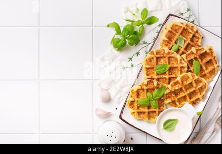 Cialde di zucchine fatte in casa con formaggio, sause e basilico in foglie su sfondo bianco. Concetto di cibo dieta del keto. Messa a fuoco selettiva. Foto Stock