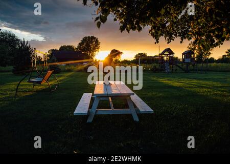 piccolo ragazzo che gioca al tramonto sul tavolo da picnic Foto Stock