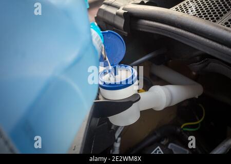 aggiunta di liquido lavaparabrezza invernale nella vettura Foto Stock