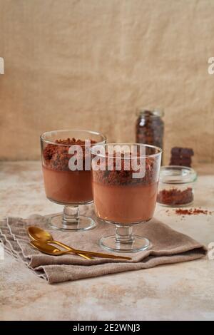 Deliziosa mousse al cioccolato da dessert con brownie in vasetti di vetro su una base di ardesia leggera, pietra o cemento. Foto Stock