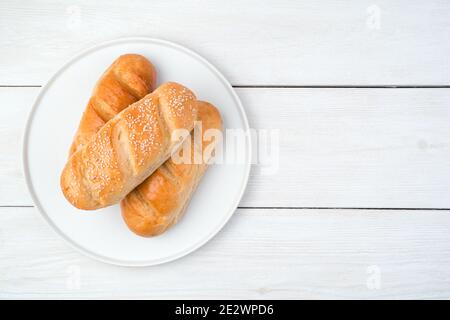 Pane fresco su un piatto piatto su uno sfondo di legno chiaro. Foto Stock