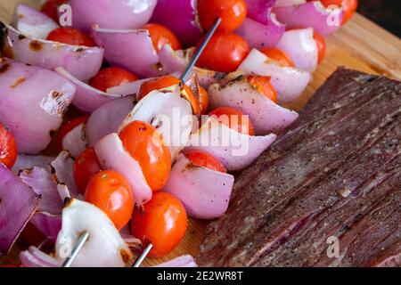 Bistecca alla griglia e spiedini di verdure: Bistecca di manzo alla griglia e spiedini di pomodori d'uva e cipolle rosse Foto Stock