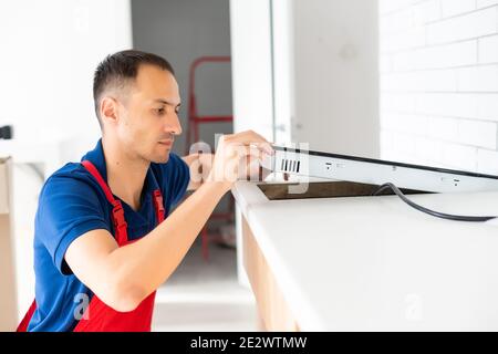 Installazione di fornelli a induzione piano di cottura o da parte di un maestro. Foto Stock
