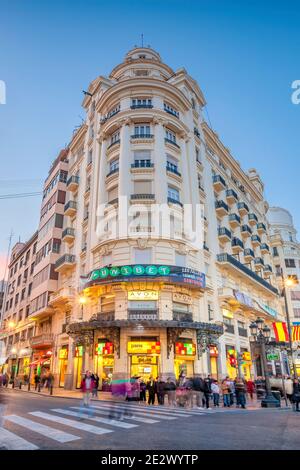 Attraversa la strada con le persone sotto una facciata ornata nel centro di Valencia in Spagna in serata. Foto Stock