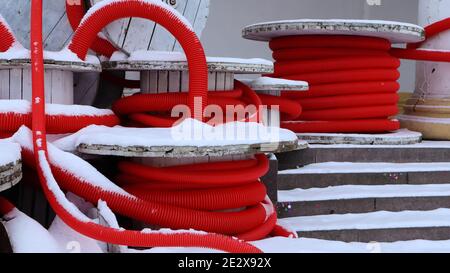 Grandi bobine di tubo corrugato flessibile rosso utilizzate per proteggere i cavi negli impianti elettrici. Un sacco di tubo flessibile in plastica di polietilene colorato utilizzato in contro Foto Stock