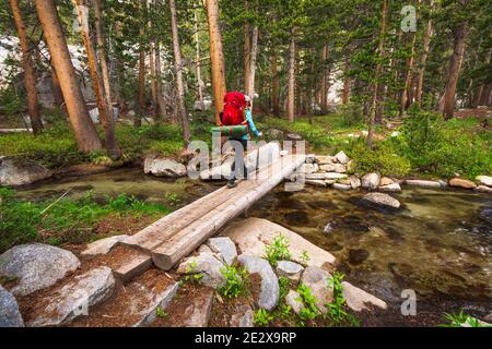 Backpacker che attraversa il torrente nella riserva naturale di John Muir, Sierra Nevada Mountains, California Stati Uniti Foto Stock