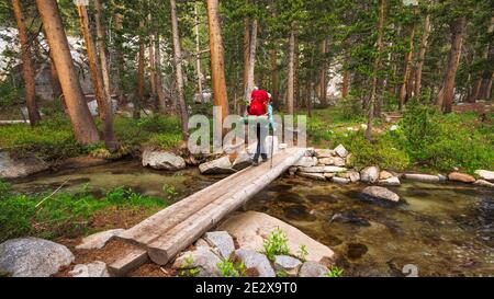Backpacker che attraversa il torrente nella riserva naturale di John Muir, Sierra Nevada Mountains, California Stati Uniti Foto Stock