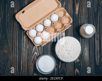ingredienti per torte: farina, zucchero, uova su scrivania in legno, piatto Foto Stock