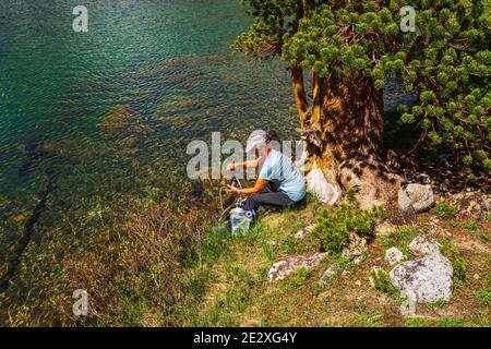 Escursionista purificante acqua sulla riva del Treasure Lake, John Muir Wilderness, Sierra Nevada Mountains, California USA Foto Stock