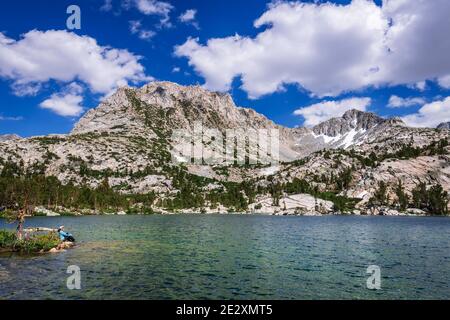 Escursionista sulla riva del Treasure Lake sotto la Sierra Crest, John Muir Wilderness, Sierra Nevada Mountains, California USA Foto Stock