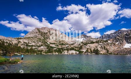 Escursionista sulla riva del Treasure Lake sotto la Sierra Crest, John Muir Wilderness, Sierra Nevada Mountains, California USA Foto Stock