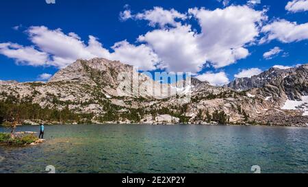 Escursionista sulla riva del Treasure Lake sotto la Sierra Crest, John Muir Wilderness, Sierra Nevada Mountains, California USA Foto Stock