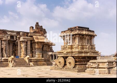 Hampi, Karnataka, India - 5 novembre 2013: Tempio Vijaya Vitthala. Carro di pietra marrone di fronte al santuario sotto il paesaggio blu nuvoloso. Foto Stock