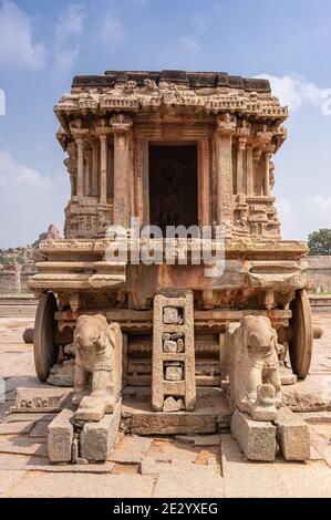 Hampi, Karnataka, India - 5 novembre 2013: Tempio Vijaya Vitthala. Primo piano di carro di pietra marrone dalla parte anteriore sotto il paesaggio blu nuvoloso. Elefanti dentro Foto Stock