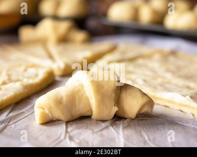 Primo piano del rullo a mezzaluna. L'impasto di lievito allevato è stato arrotolato per i rotoli di mezzaluna. L'impasto è stato lathered in burro. Rulli aggiuntivi nella parte posteriore Foto Stock