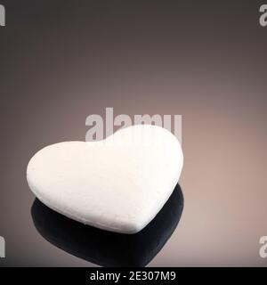 Cuore 3d bianco in polistirene, su sfondo scuro con posto per il testo. Concetto di amore artificiale, cuore congelato. Foto studio. San Valentino. Si Foto Stock