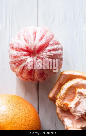 Pompelmo intero e sbucciato. Piatto minimalista su uno sfondo chiaro con spazio per la copia. Concetto di cibo sano Foto Stock