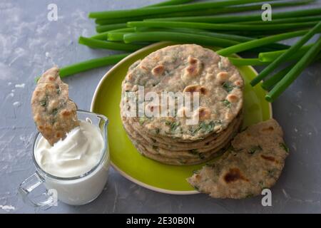 Pane integrale di segale di grano con cipolle verdi su fondo grigio. Cibo sano fatto in casa Foto Stock