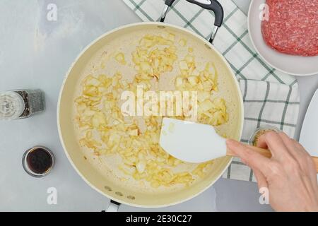 Cipolla tritata su padella. Primo piano cottura, mani donna, piatto Foto Stock