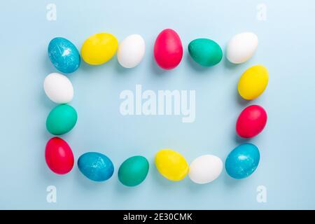 Cornice di uova di pasqua multicolore su sfondo blu. Composizione pasquale. Spazio di copia. Mockup - immagine Foto Stock
