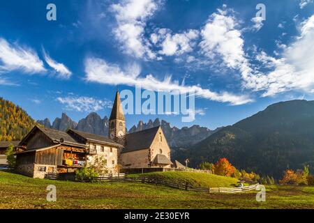 Vista della caratteristica chiesa e della città di San Magdalena con l'Odle sullo sfondo. Val di Funes, Alpi Dolomiti, Trentino Alto Adige, Italia. Foto Stock