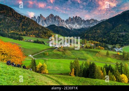 Vista di un bellissimo tramonto sul massiccio dell'Odle con la città e la chiesa di San Magdalena. Val di Funes, Alpi Dolomiti, Trentino Alto Adige, Italia. Foto Stock