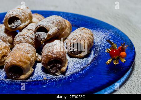 Cannoli al cioccolato. Dolci italiani al cioccolato su piatto blu e fondo bianco. Foto Stock