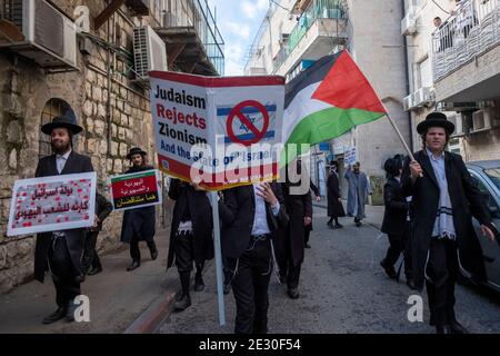 I membri di Neturei Karta, un movimento ebreo ultra-ortodosso frangia all'interno del blocco anti-sionista portano la bandiera palestinese e gridano slogan mentre camminano attraverso il quartiere religioso di Mea Shearim il 14 gennaio 2021, a Gerusalemme, Israele. Neturei Karta si oppone al sionismo e chiede uno 'smantellamento pacifico' dello Stato d'Israele, nella convinzione che agli ebrei è vietato avere il proprio stato fino all'avvento del Messia ebraico e che lo stato d'Israele è una ribellione contro Dio. Foto Stock