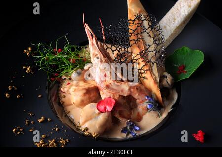 Frutti di mare assortiti con gamberi, capesante e cozze, in salsa, su sfondo scuro Foto Stock