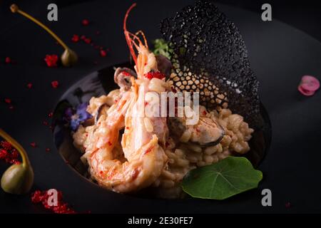 Risotto con gamberi e cozze, su fondo nero Foto Stock