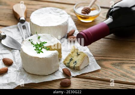 Vari tipi di formaggio, formaggio blu, bree, camambert e vino su un tavolo di legno Foto Stock