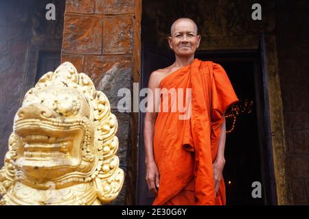 Kampot, Cambogia - 22 SETTEMBRE 2013: Monaco buddista Khmer in piedi vicino a una statua di Singha Khmer e guardando la macchina fotografica. PRAM di Wat Sampov. Foto Stock
