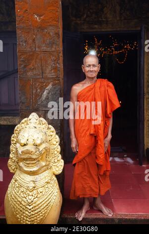 Kampot, Cambogia - 22 SETTEMBRE 2013: Monaco buddista Khmer in piedi vicino a una statua di Singha Khmer e guardando la macchina fotografica. PRAM di Wat Sampov. Foto Stock