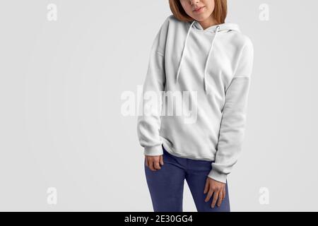 Serie di abiti mockup. Bella donna gracile in una felpa bianca con cappuccio e pantaloni blu isolato sullo studio vuoto backgrounds.Frontal posa. Il modello può utilizzare i Foto Stock