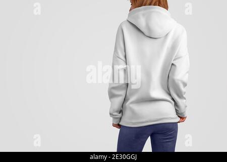 Serie di abiti mockup. Donna beaty gracile in una felpa con cappuccio bianca e pantaloni blu isolati sullo sfondo vuoto dello studio. Posa posteriore. Il modello può essere utilizzato in y Foto Stock
