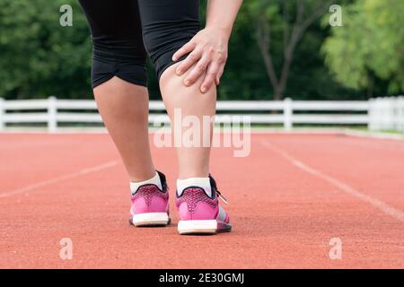 Dolore muscolare del corridore della donna di mezza età durante l'allenamento all'aperto Foto Stock