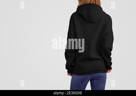 Serie di abiti mockup. Donna beaty gracile in una felpa con cappuccio nera e pantaloni blu isolati sugli sfondi vuoti dello studio. Posa posteriore. Il modello può essere utilizzato in y Foto Stock