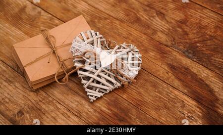 Un sacco di buste da carta kraft legato con stringa con cuore bianco fatto a mano su sfondo di legno Foto Stock